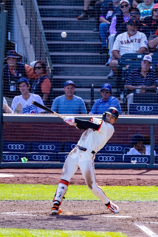 San Francisco Giants batter swinging, ball in mid-air, Dodgers fans in the stands
